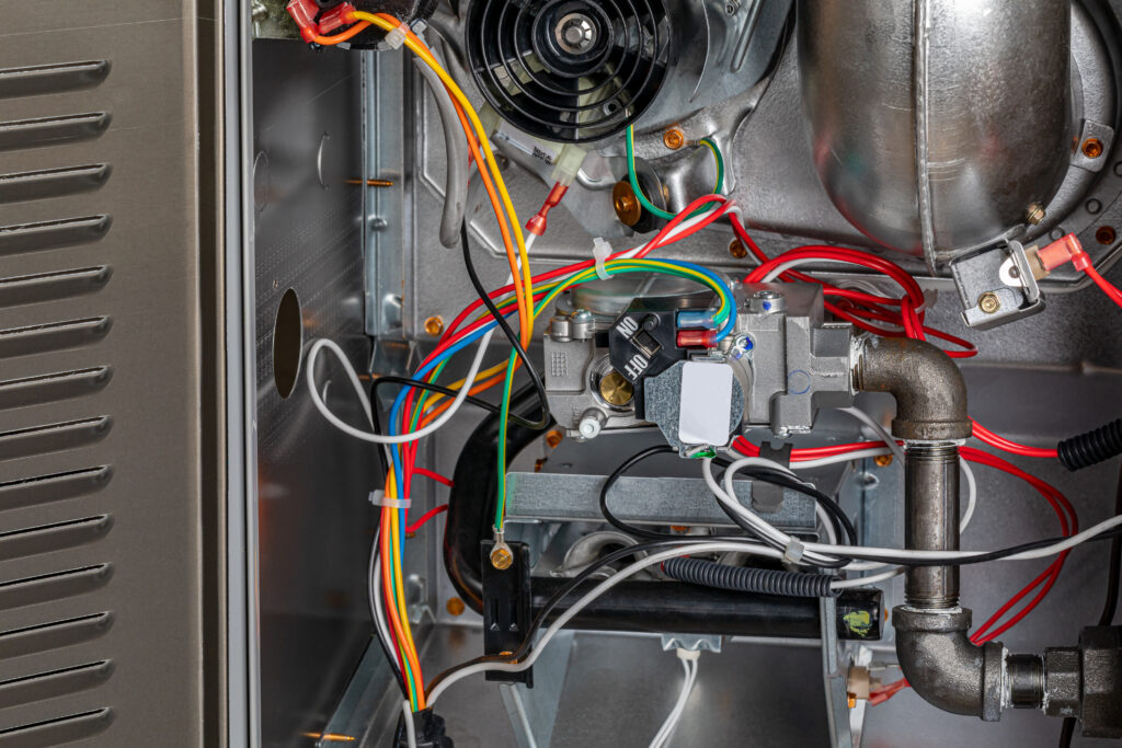 A closeup picture of the internals of a gas furnace centered on the gas furnace valve