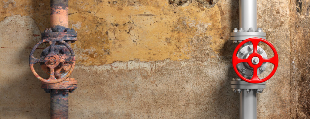 Old and new industrial pipelines and valves on weathered wall