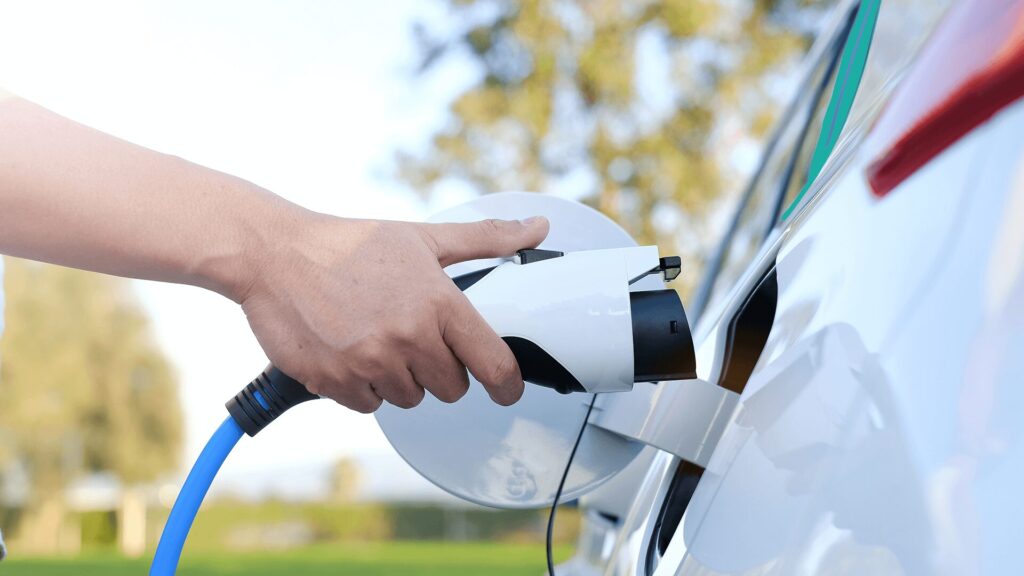 Hand plugging in an EV charger to an electric vehicle outdoors in Tyler, Texas