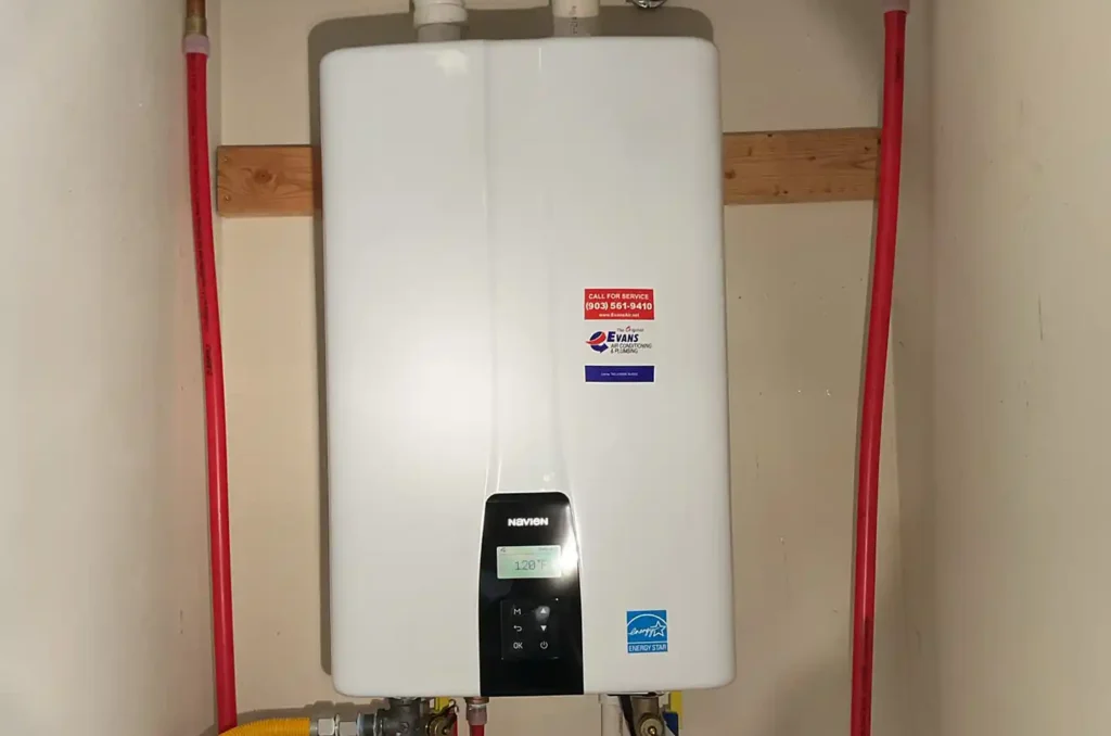Tankless water heater installation with red and yellow supply lines mounted on wall