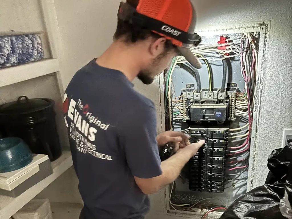 Evans electrician working on an electrical breaker panel during a service call