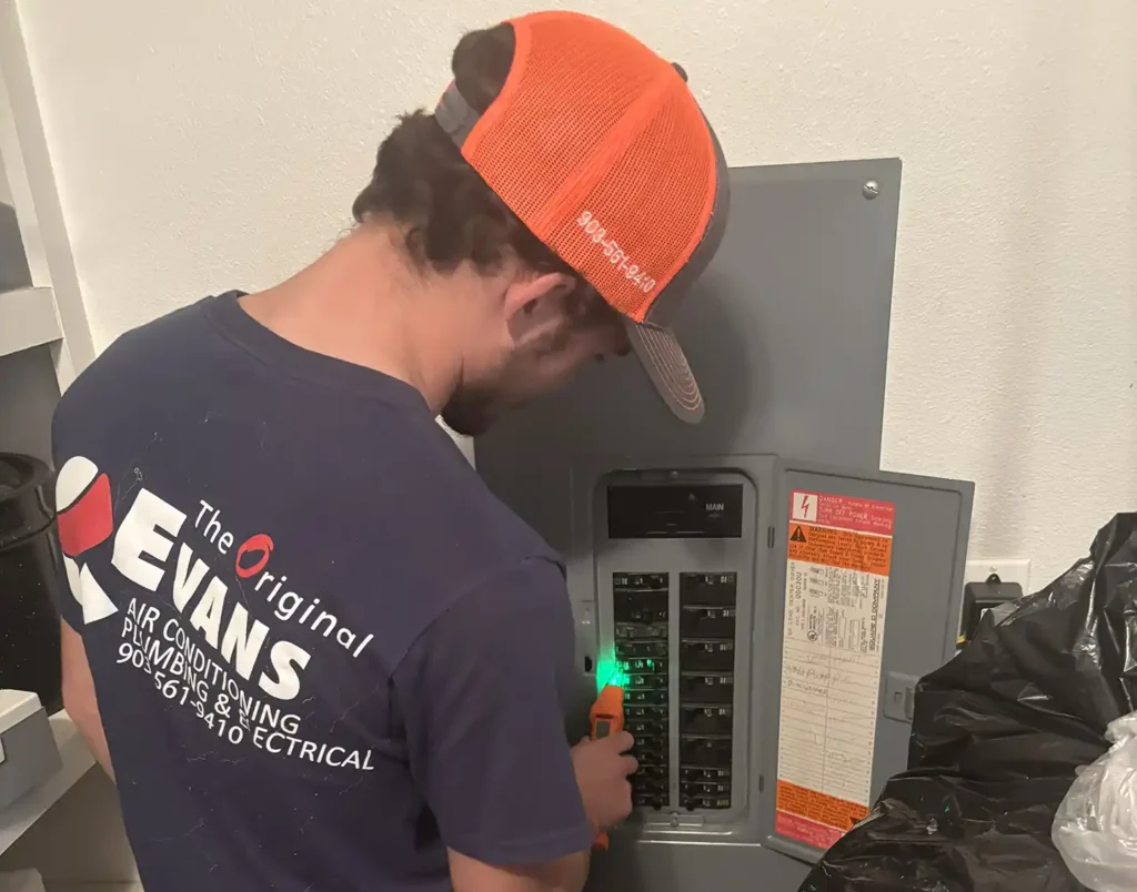 Evans electrician in branded uniform and tool belt servicing a residential electrical breaker panel