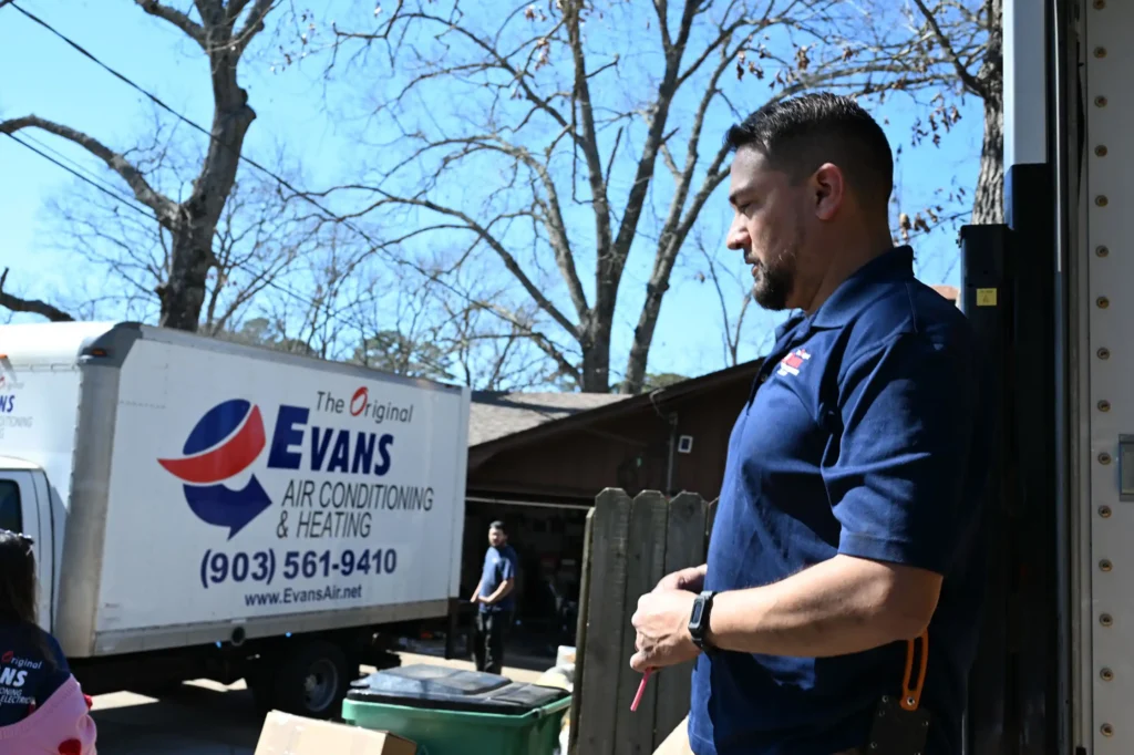 Evans Air technician standing beside an Evans Air service truck with another technician in the background